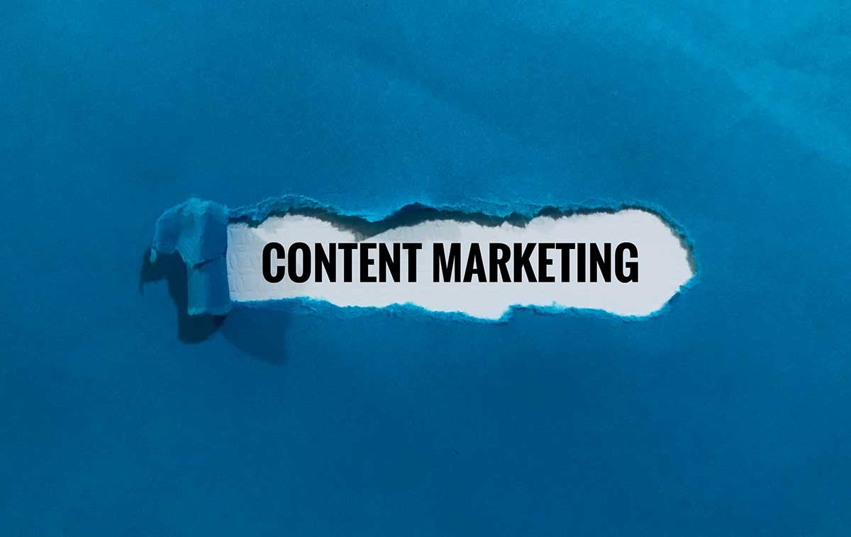 feuille de papier bleue déchirée en son centre pour faire apparaître les mots "content marketing"